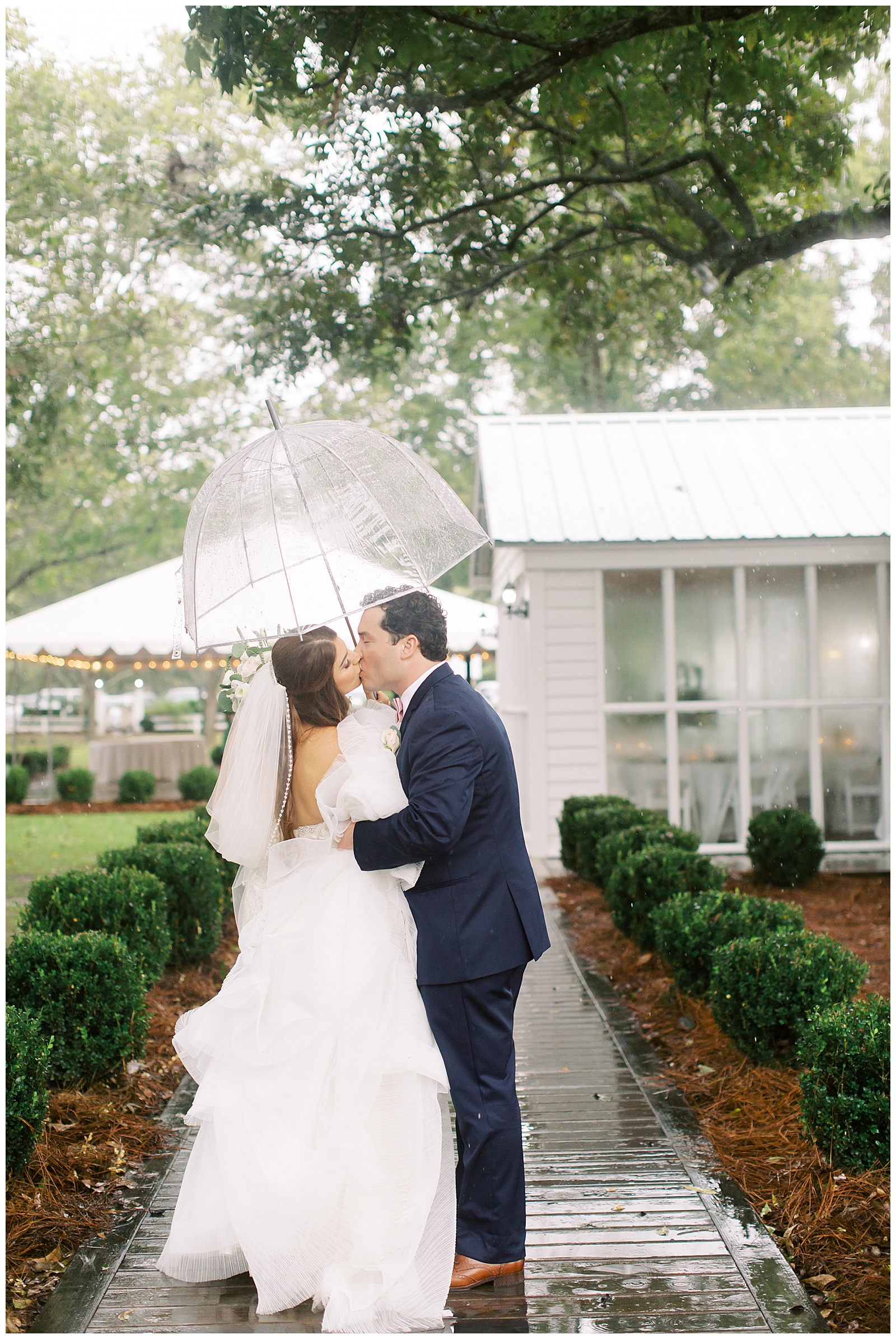 bride and groom kissing under umbrella on wedding day